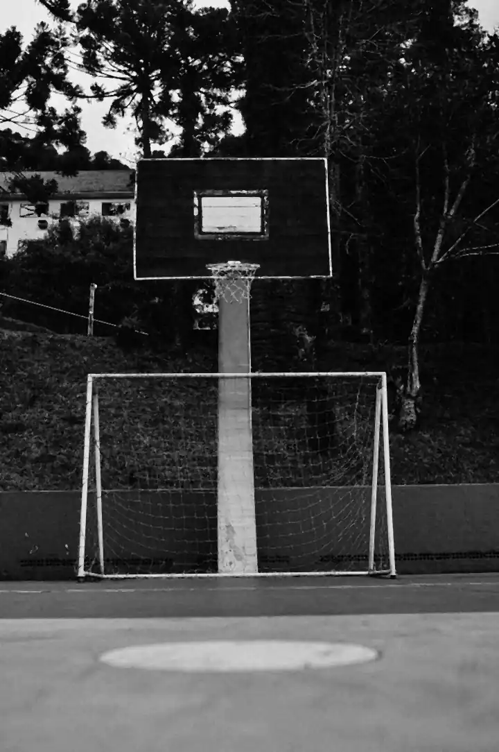 Un tablero de baloncesto sobre un arco de microfútbol, en la misma cancha de un parque.
